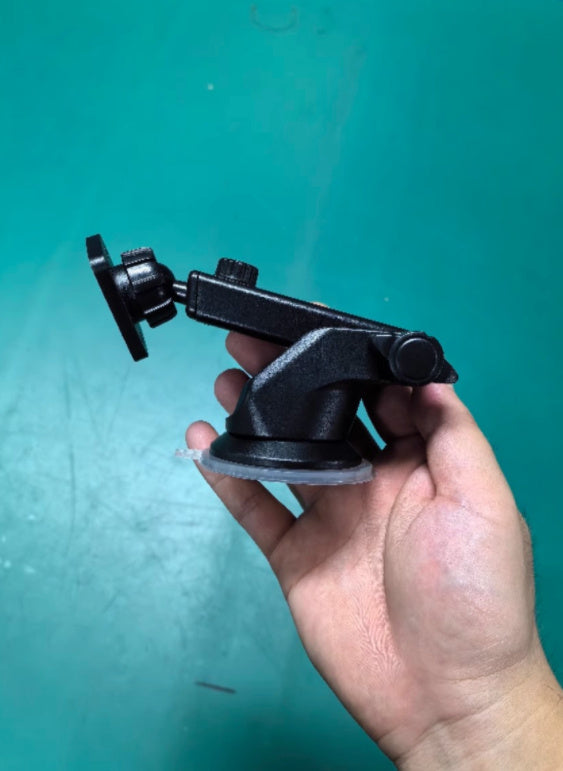 Hand holding a black suction cup mount against a teal background